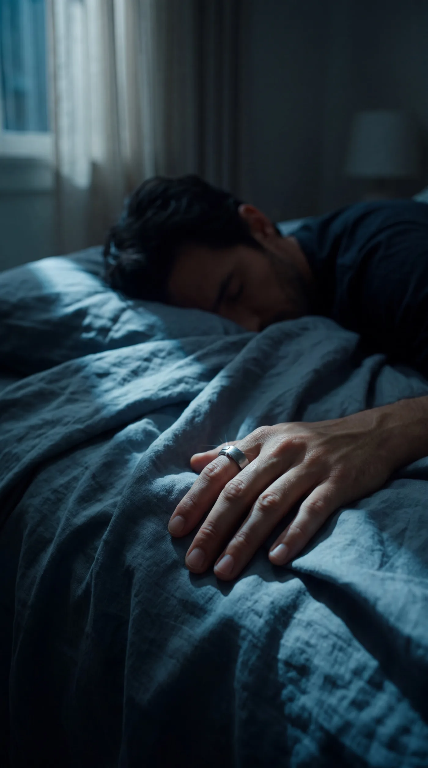 A hand with the ring resting on the chest of a sleeping man at night