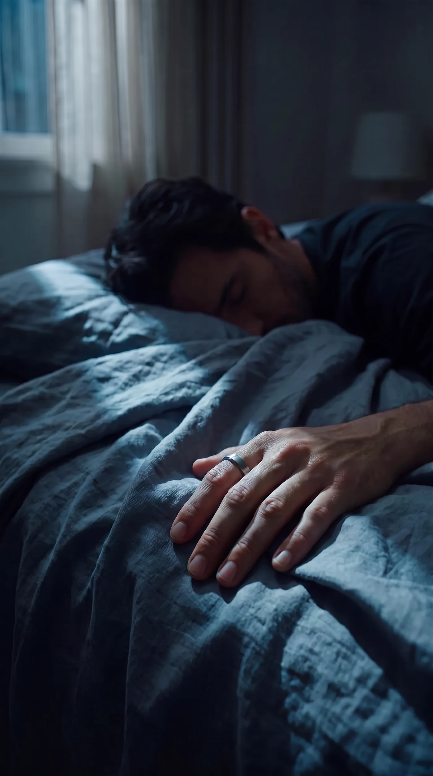 A hand with the ring resting on the chest of a sleeping man at night