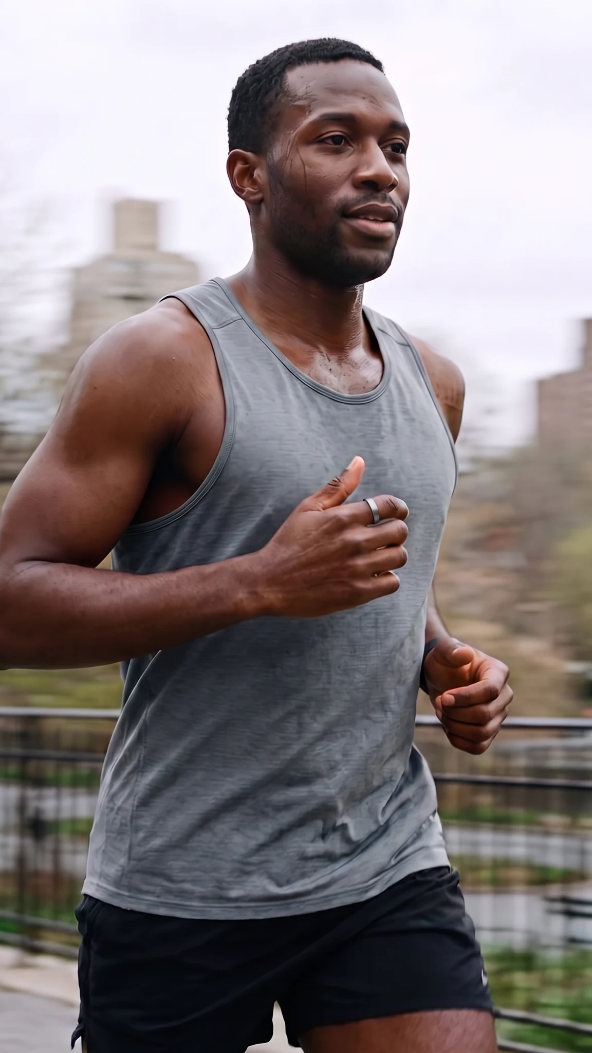 A man running through a city park, the background smeared with motion blur, the ring on his index finger
